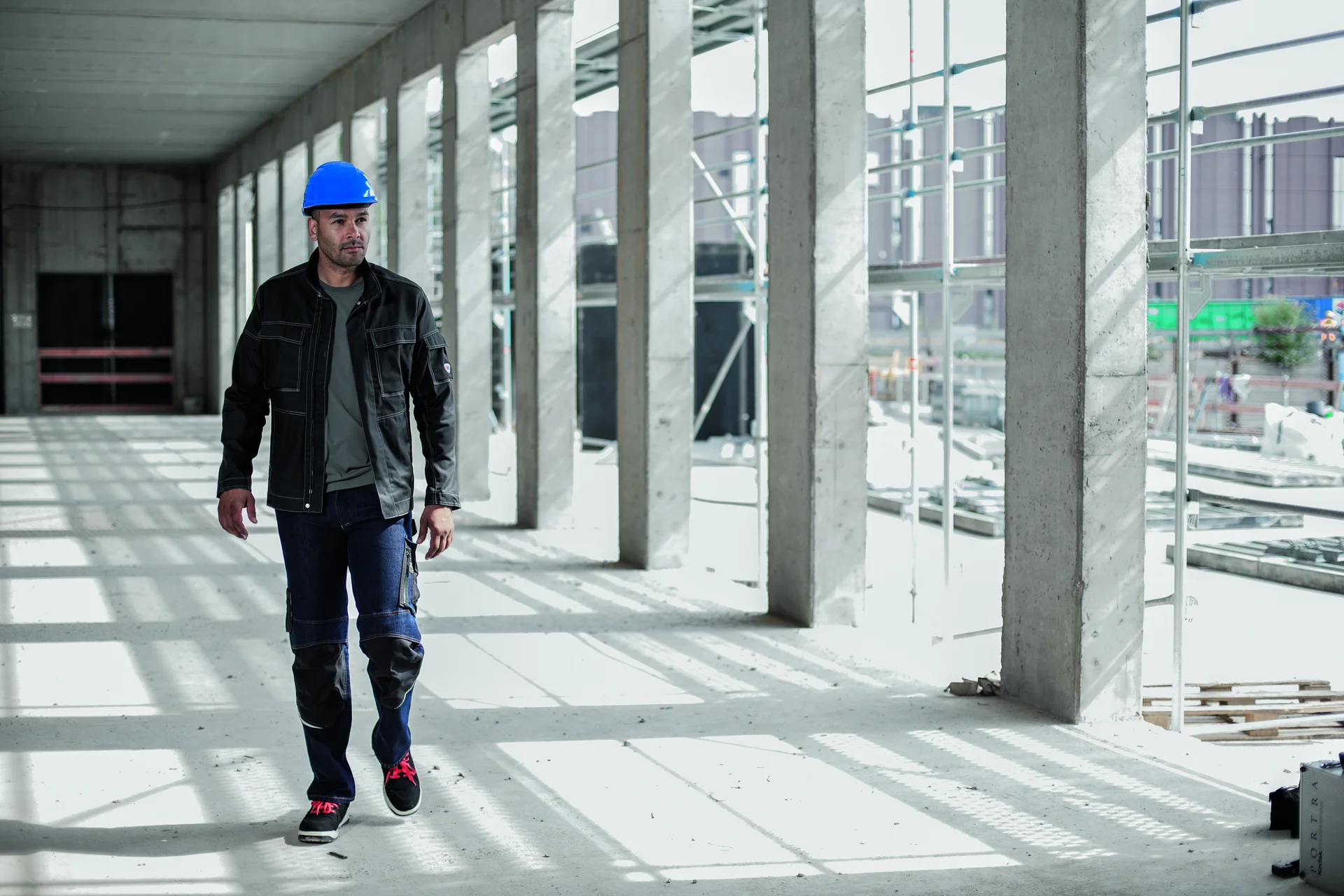 Ein Mann in Arbeitskleidung & PSA auf einer Baustelle