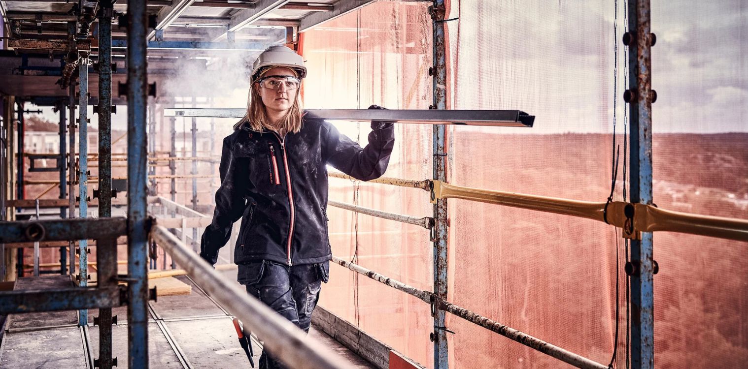 Eine Frau trägt Gegenstände auf einer Baustelle