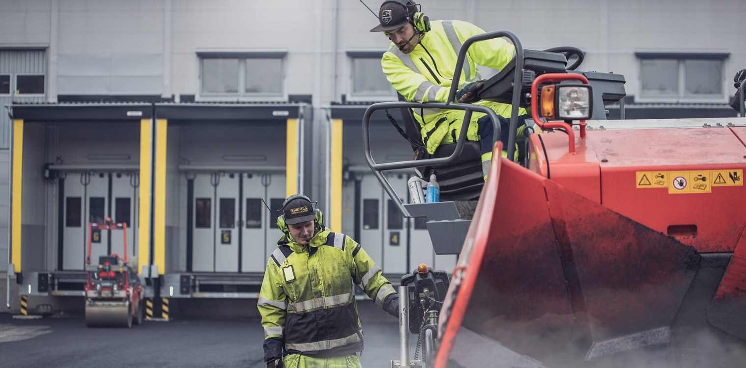 Zwei Mitarbeiter eines Versorgungsunternehmens arbeiten mit großen Gerät und tragen Sicherheitskleidung